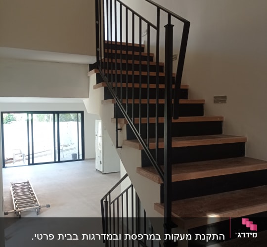 מעקה מתכת שחור על מדרגות עץ בבית